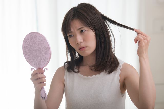 手鏡で髪をチェックする女性